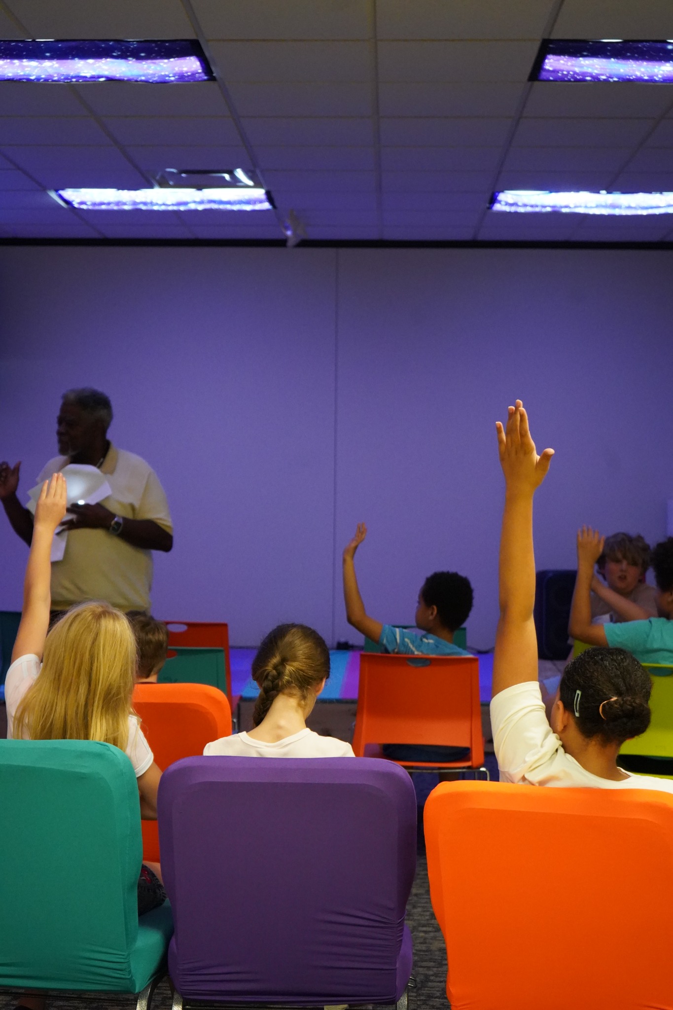 Children raising their hands during a Bethesda Kids lesson.